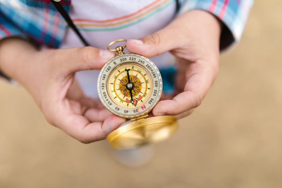 gold and silver compass on persons hand